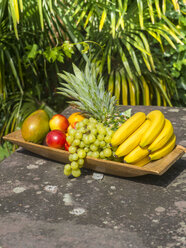 Wooden plate of bananas, pineapple, green grapes, mango and nectarines - AMF004132