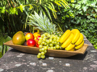 Wooden plate of bananas, pineapple, green grapes, mango and nectarines - AMF004133