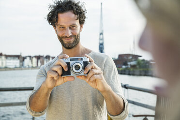 Germany, Luebeck, man taking picture at the waterside - FMKF001897