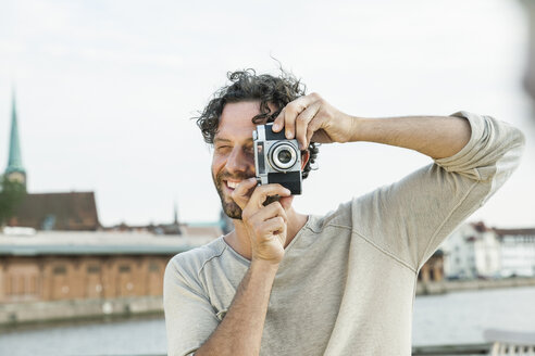 Germany, Luebeck, man taking picture at the waterside - FMKF001868