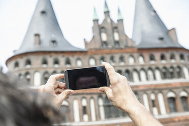 Germany, Luebeck, man taking picture in front of the Holsten Gate - FMKF001880