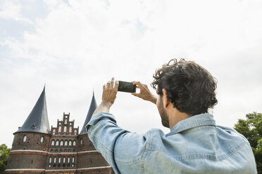 Deutschland, Lübeck, Mann beim Fotografieren vor dem Holstentor - FMKF001881