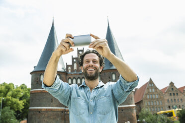 Germany, Luebeck, man taking selfie in front of the Holsten Gate - FMKF001882