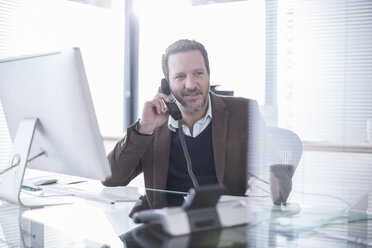 Businessman talking on phone in office - ZEF007141