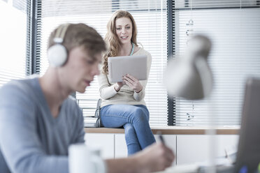 Zwei Kreativprofis mit Kopfhörern und digitalem Tablet im Büro - ZEF007174