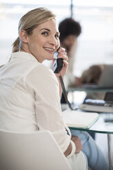 Lächelnde Frau am Telefon im Büro - ZEF007463