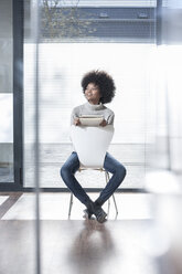 Woman sitting on a chair in office thinking - ZEF007195