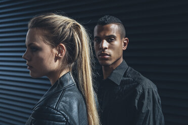 Schwarz gekleidetes junges Paar vor einer schwarzen Fassade - CHAF001385
