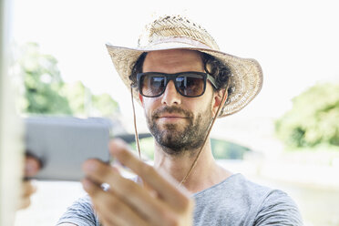 Mann mit Strohhut und Sonnenbrille macht ein Selfie - FMKF001916