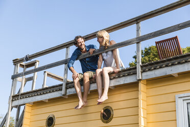 Couple sitting on roof deck of a house boat - FMKF001934