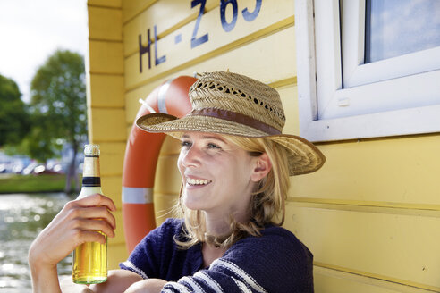 Smiling woman on a house boat with beer bottle - FMKF001938
