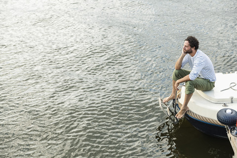 Relaxed man sitting on boat stock photo