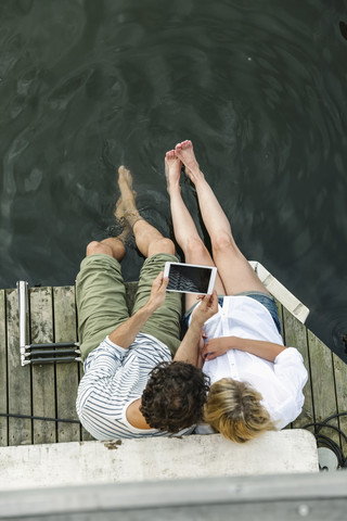 Pärchen teilt sich digitales Tablet am Wasser, lizenzfreies Stockfoto