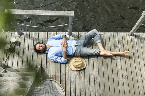 Mann auf Plattform am Wasser liegend, lizenzfreies Stockfoto