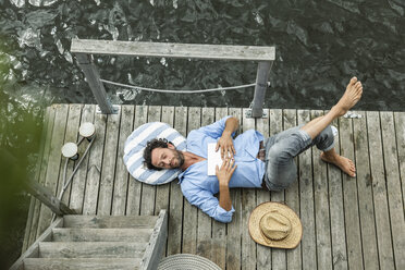 Man lying on platform at the waterside - FMKF001970