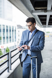 Businessman on business trip using his mini tablet - UUF005350