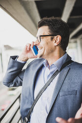 Smiling businessman telephoning with smartphone - UUF005357