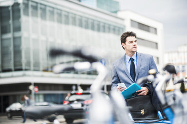 Germany, Ludwigshafen, businessman with briefcase, file and smartphone - UUF005366