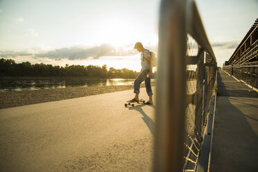 Mann mit Skateboard in der Abenddämmerung - UUF005397