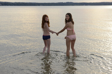 Deutschland, Oberbayern, zwei Mädchen waten Hand in Hand im Wasser des Starnberger Sees - LBF001178