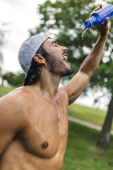 Athletic young man refreshing after training in the park - MGOF000498