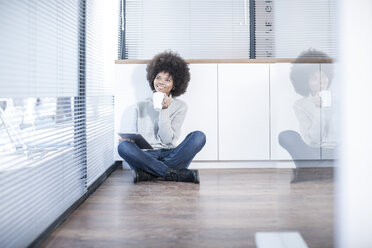 Woman sitting on the floor in office thinking - ZEF007214