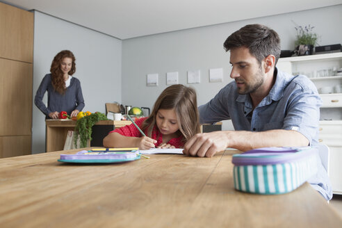 Kleines Mädchen macht am Küchentisch Hausaufgaben, während ihr Vater sie beobachtet - RBF003370