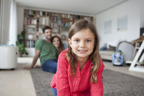 Portrait of smiling little girl and her parents in the background in the living room stock photo