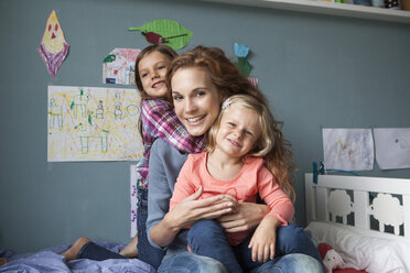 Portrait of woman with her little daughters in children's room - RBF003404