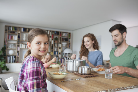 Portrait of little girl sitting at dining table with her parents and sister stock photo