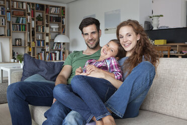 Portrait of happy couple and little daughter on the couch at home - RBF003422