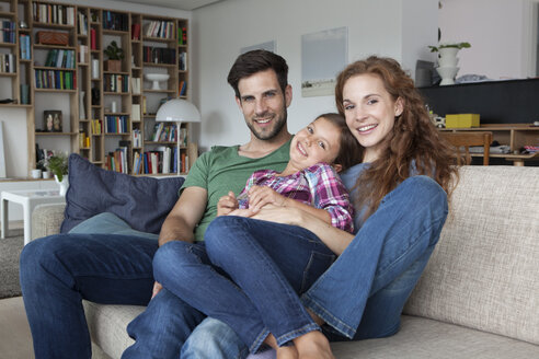 Porträt des glücklichen Paares und der kleinen Tochter auf der Couch zu Hause - RBF003422