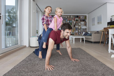 Mann spielt mit seinen kleinen Töchtern im Wohnzimmer - RBF003427