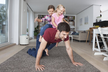 Mann spielt mit seinen kleinen Töchtern im Wohnzimmer - RBF003428