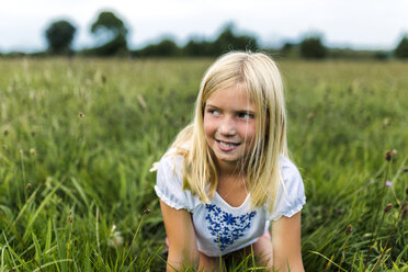 Portrait of girl kneeling on a meadow watching something - MGOF000500