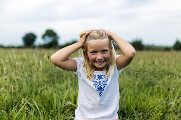 Portrait of smiling girl with hands in her hair on a meadow - MGOF000501
