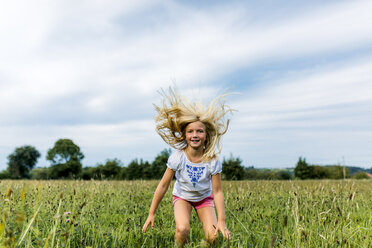Porträt eines Mädchens, das auf einer Wiese in die Luft springt - MGOF000504