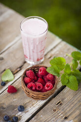 Frischer Himbeermilchshake im Glas, Himbeeren im Korb - KSWF001553