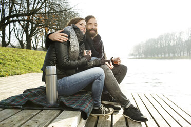 Glückliches Paar mit heißem Getränk am Flussufer im Herbst - PESF000129