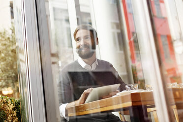 Smiling young man using digital tablet in restaurant - PESF000150