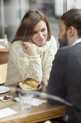 Smiling young woman looking at man at restaurant table - PESF000154