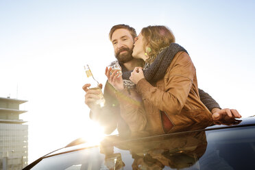 Happy couple looking through sunroof of a car sharing a scarf - PESF000166