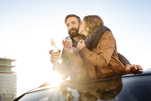 Glückliches Paar, das durch das Schiebedach eines Autos schaut und einen Schal teilt - PESF000166
