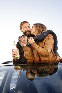 Glückliches Paar, das durch das Schiebedach eines Autos schaut und einen Schal teilt - PESF000167