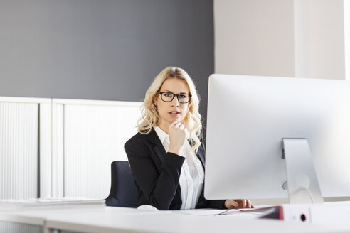 Porträt einer blonden Frau am Schreibtisch im Büro - PESF000043