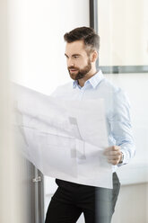 Man in office looking at construction plan - PESF000050