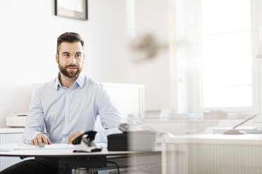 Mann sitzt am Schreibtisch im Büro - PESF000051