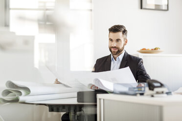 Man in office holding construction plan - PESF000056