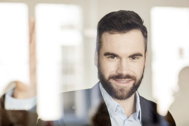 Portrait of smiling businessman behind glass wall - PESF000058