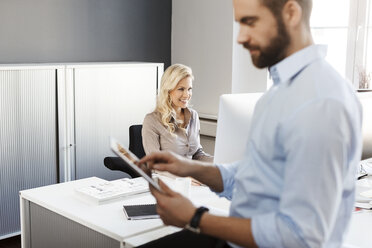 Two colleagues in office with digital tablet and computer - PESF000125